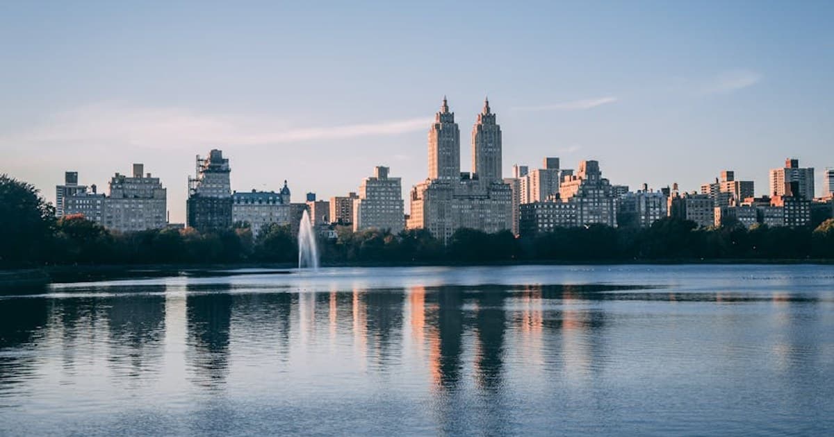 A stunning view of New York City's skyline with Central Park Reservoir reflecting the skyscrapers at dusk.