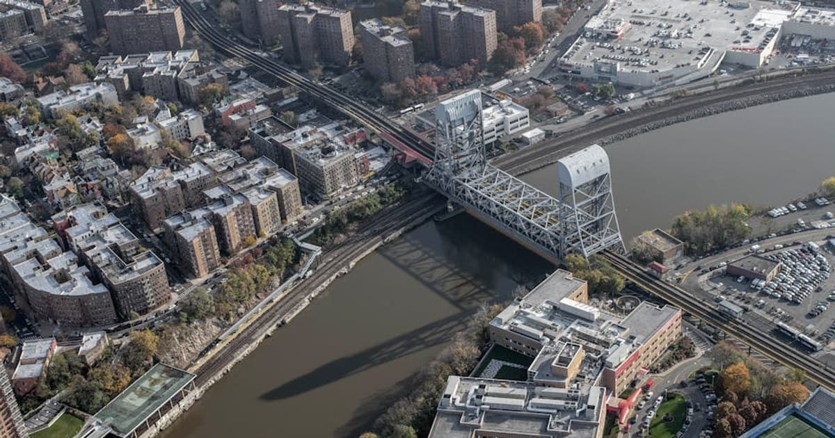 Aerial shot of New York City's urban landscape featuring a bridge over a river and residential buildings.