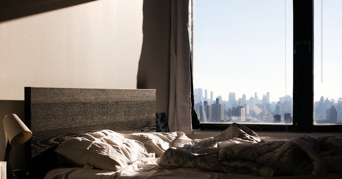Modern bedroom with a stunning view of the New York City skyline through the window.