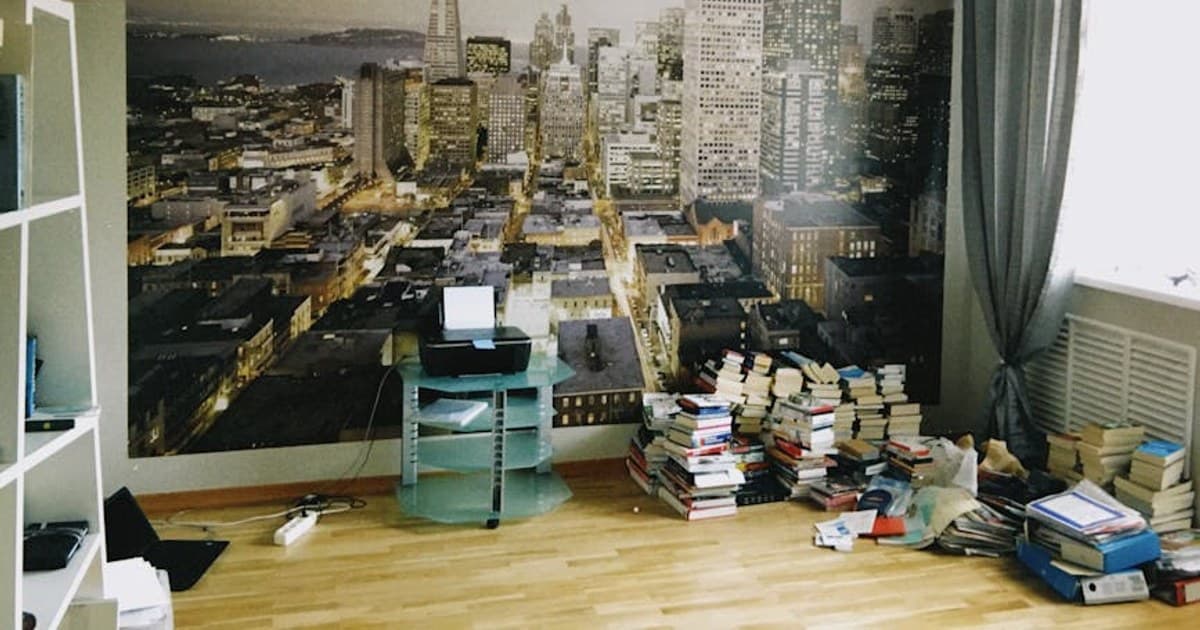 Room interior with a large San Francisco skyline wallpaper and stacks of books.