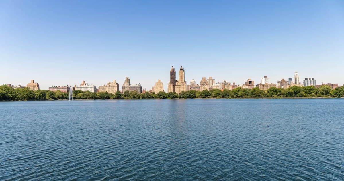 Breathtaking view of NYC skyline across Central Park reservoir on a sunny day.
