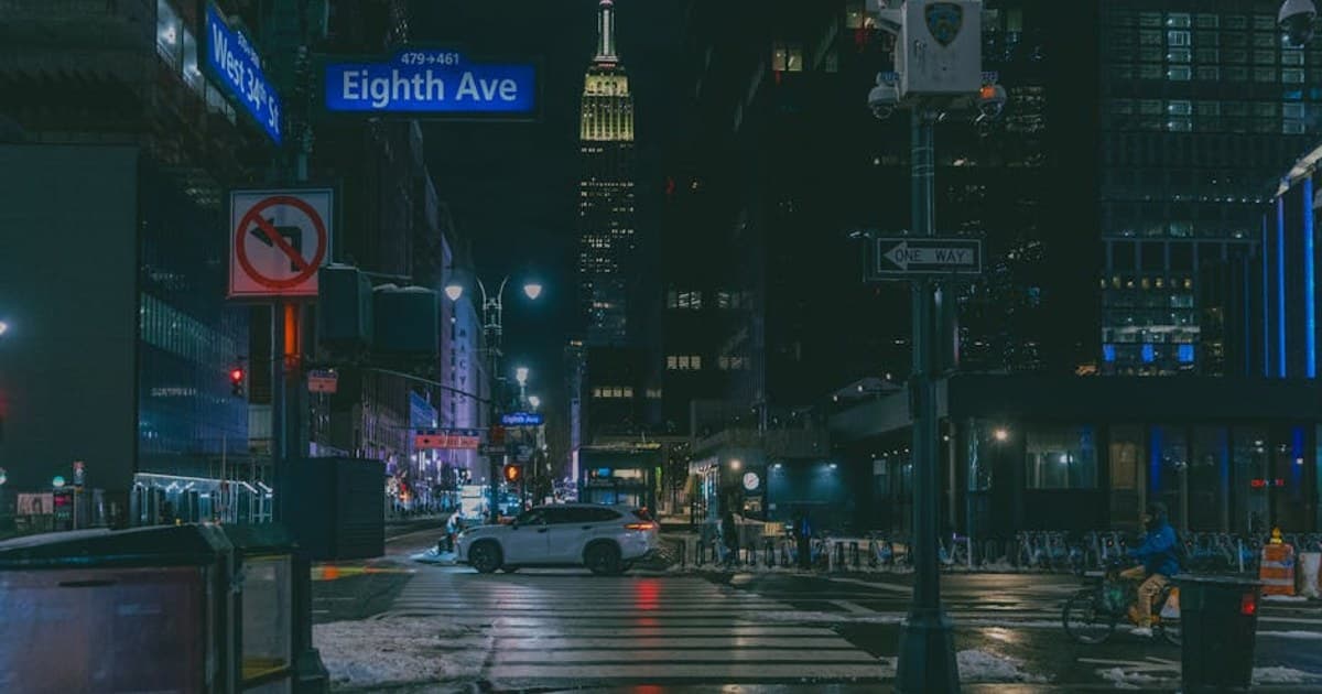 Atmospheric night scene of Eighth Avenue with the Empire State Building in New York City.