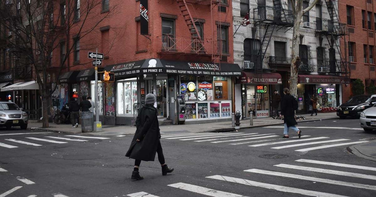 Pedestrians crossing a street at an intersection in Brooklyn, NYC with shops and apartments.