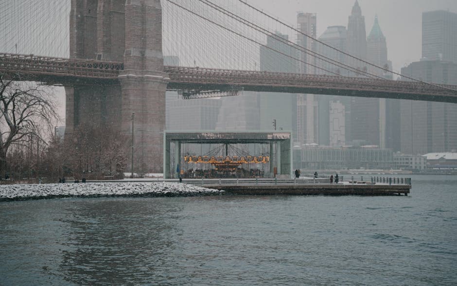 Snowy view of Brooklyn Bridge and Jane's Carousel in New York City during winter.