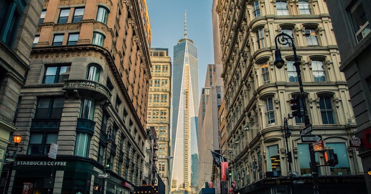 Street view of One World Trade Center in New York City surrounded by urban architecture and city life.
