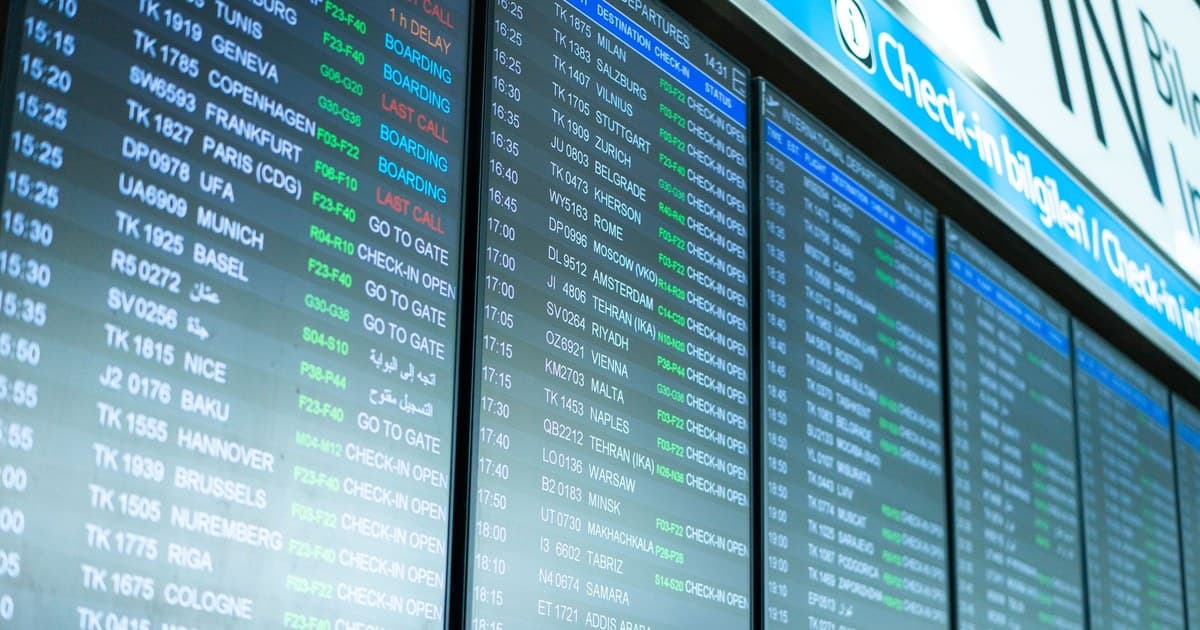 Digital screens display flight information and schedules at an airport terminal.